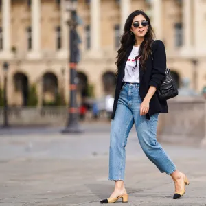 PARIS, FRANCE - FEBRUARY 25: Camille Grandguillote wears sunglasses, a black blazer jacket from Sezane, a black leather bag from Kate Lee, a white t-shirt from "Pas le Time", blue denim jeans pants from Asos, Chanel beige and black slingback shoes, on February 25, 2021 in Paris, France. (Photo by Edward Berthelot/Getty Images)