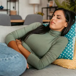 Young woman lying on the sofa and having period cramps.