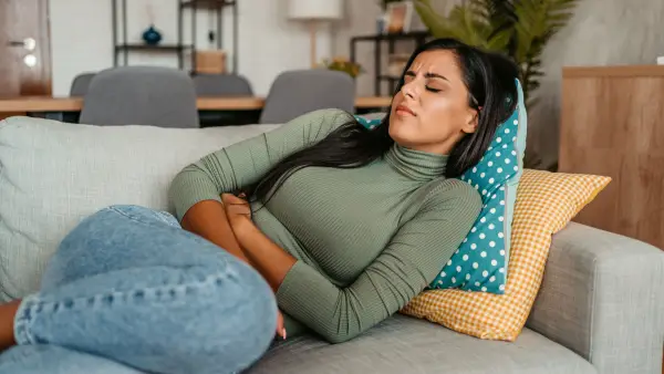 Young woman lying on the sofa and having period cramps.