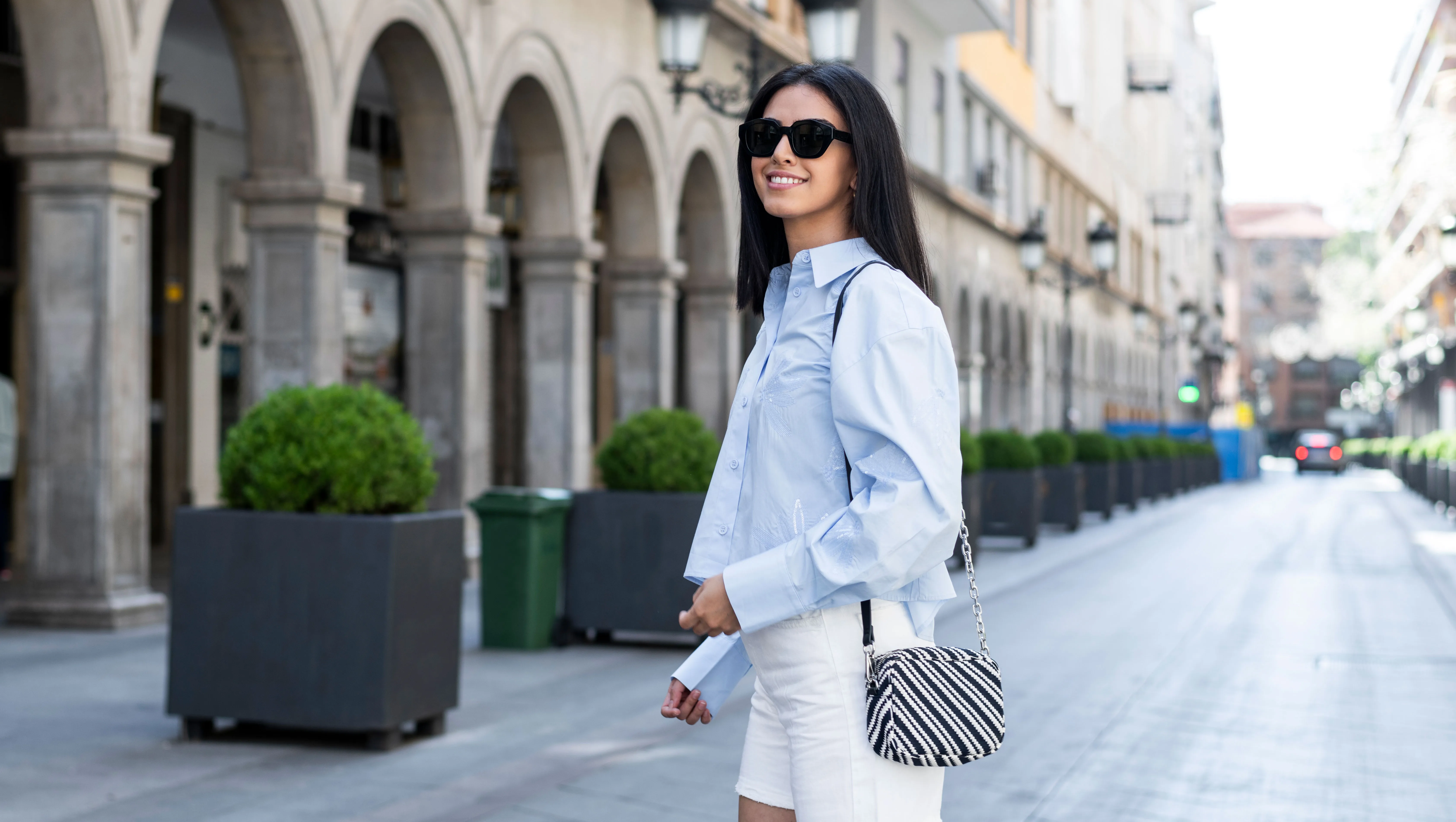 Young woman standing on street in front of building - stock photo