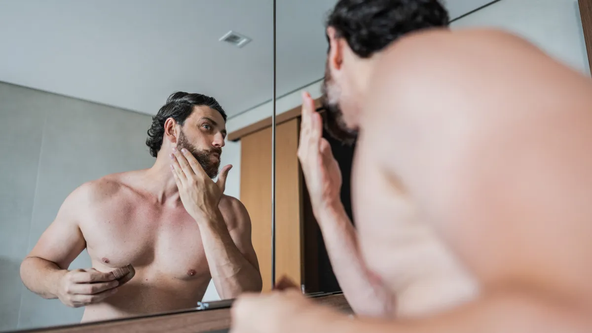 Mid adult man fixing his beard in the bathroom at home