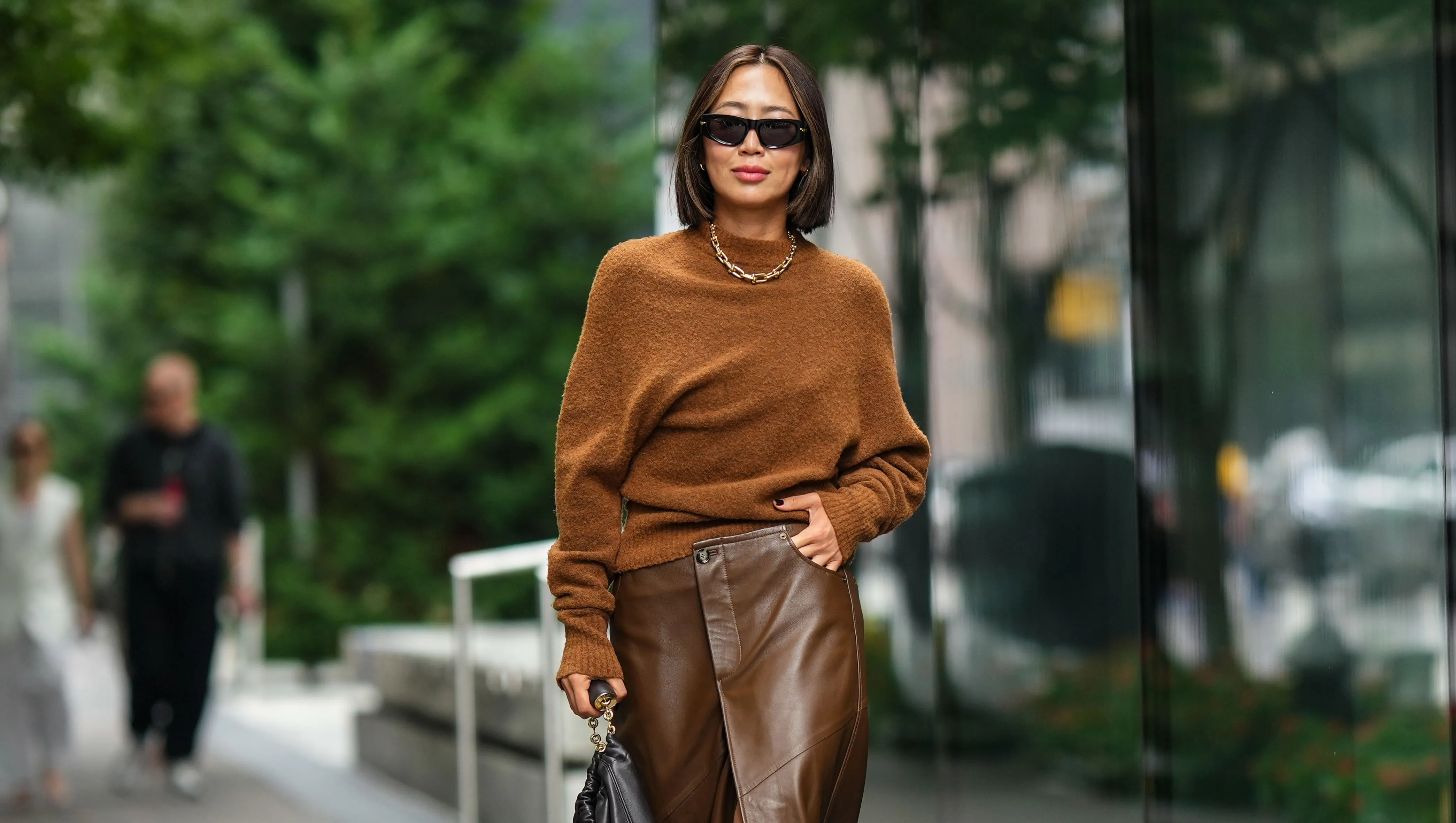NEW YORK, NEW YORK - SEPTEMBER 09: Aimee Song wears sunglasses, a necklace, a brown wool pullover, a brown leather skirt, a black leather bag, brown knee-high boots, outside Proenza Schouler, during New York Fashion Week, on September 09, 2023 in New York City. (Photo by Edward Berthelot/Getty Images)