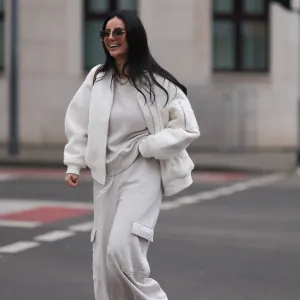 COLOGNE, GERMANY - FEBRUARY 14: Tara Tut seen wearing Gucci brown sunglasses, gold earrings, gold necklace, Zara creamy white cotton oversized sweater, matching Zara creamy white jogger pants / sweatpants, H&M white boucle bomber jacket, Longchamp brown nylon shopper bag, on February 14, 2024 in Cologne, Germany. (Photo by Jeremy Moeller/Getty Images)