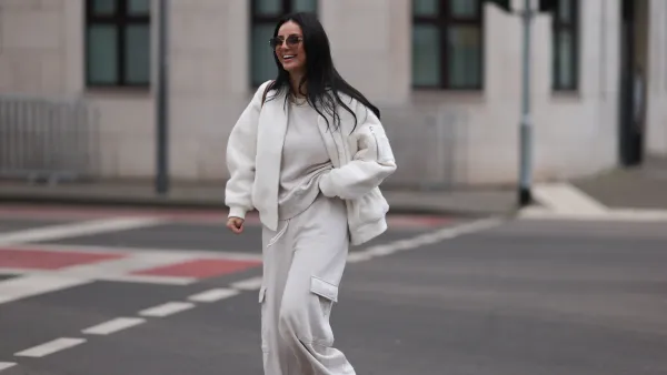 COLOGNE, GERMANY - FEBRUARY 14: Tara Tut seen wearing Gucci brown sunglasses, gold earrings, gold necklace, Zara creamy white cotton oversized sweater, matching Zara creamy white jogger pants / sweatpants, H&M white boucle bomber jacket, Longchamp brown nylon shopper bag, on February 14, 2024 in Cologne, Germany. (Photo by Jeremy Moeller/Getty Images)