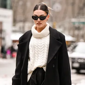 NEW YORK, NEW YORK - FEBRUARY 09: Natalie Zarra is seen wearing a black coat, cream sweater, black leather shorts, black sunglasses and Chanel bag outside the Lapointe show during NYFW F/W 2025 on February 09, 2025 in New York City. (Photo by Daniel Zuchnik/Getty Images)
