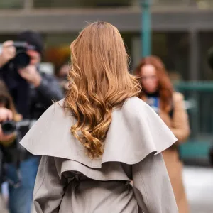 NEW YORK, NEW YORK - FEBRUARY 08: A guest wears a gray trench coat and poses in front of photographers, outside Altuzarra, during New York Fashion Week, on February 08, 2025 in New York City. (Photo by Edward Berthelot/Getty Images)