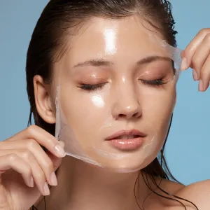 pretty female taking off purifying mask with her eyes closed, girl with wet hair removing moisturizer, fresh and clean skin