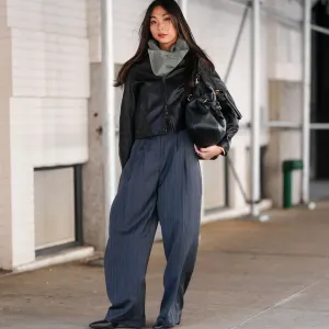 NEW YORK, NEW YORK - FEBRUARY 07: A guest wears dark gray scarf, shiny black cropped leather jacket, shiny black leather bag, dark gray pinstripe high waisted loose trouser pants, shiny black pointed toe heeled boots leather shoes, outside Theory, during the New York Fashion week Fall/Winter 2025 on February 7, 2025 in New York, New York. (Photo by Edward Berthelot/Getty Images)