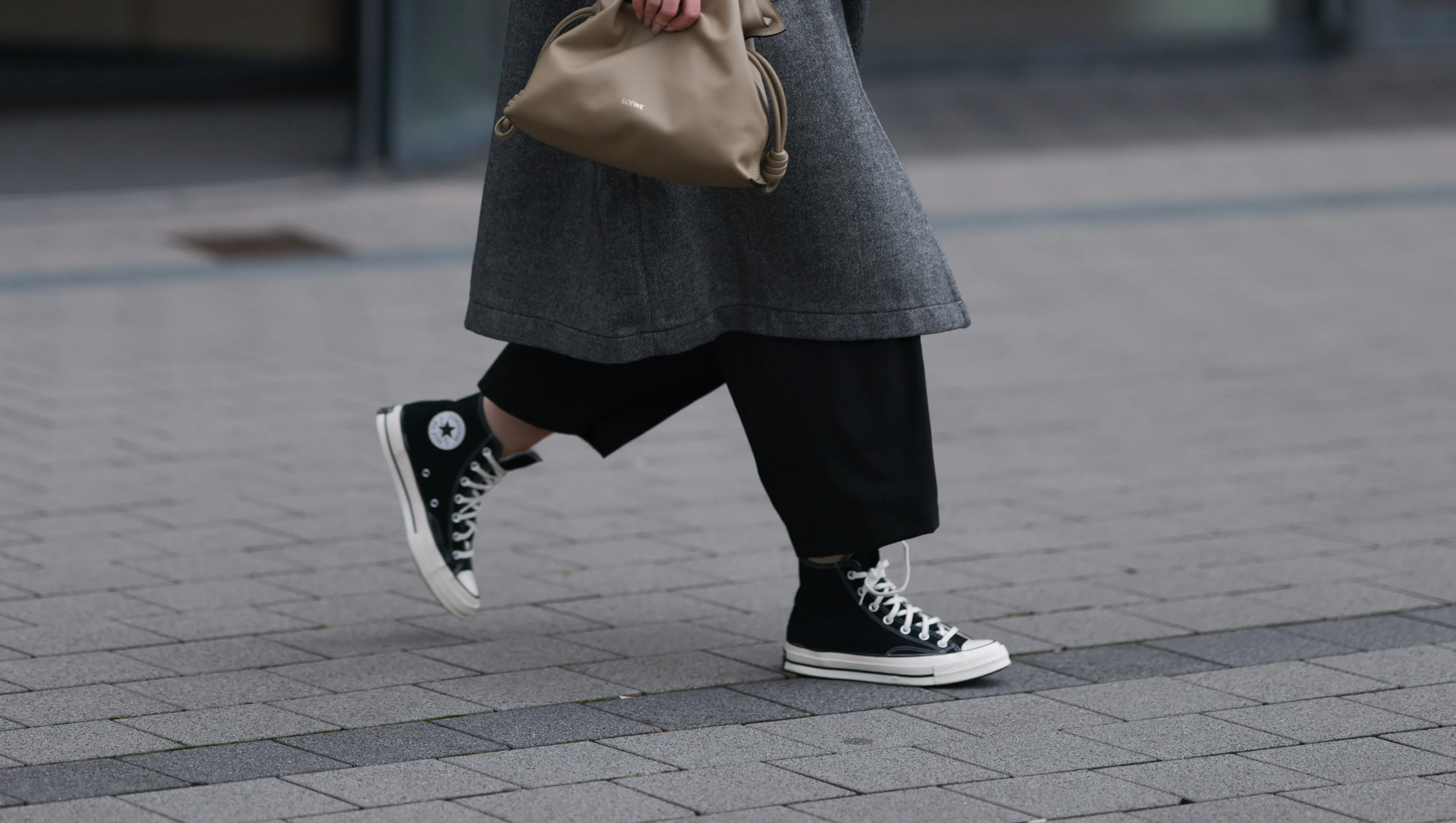 DUESSELDORF, GERMANY - NOVEMBER 08: Maria Barteczko is seen wearing oversized square-shaped aviator glasses with a black frame and narrow silver temples from Victoria Beckham; small chunky hoop earrings in silver from COS; an oversized grey wool coat with notch lapels and large pockets from WENDKYKEI; underneath a black t-shirt with a round neckline paired with black wide-legged culotte pants, both from WENDYKEI; a “Flamenco“ clutch bag in light khaki leather from Loewe; and black high top “All Star Chucks“ from Converse on November 08, 2024 in Duesseldorf, Germany. (Photo by Jeremy Moeller/Getty Images)