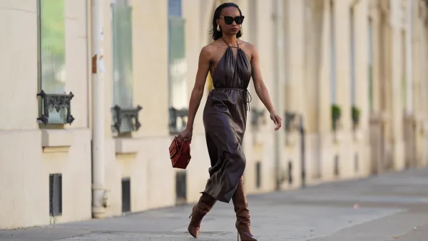 PARIS, FRANCE - APRIL 13: Emilie Joseph wears sunglasses, golden earrings, a brown leather gathered sleeveless dress, a red leather bag, brown leather boots / pointed shoes high heels with crocodile patterns, during a street style fashion photo session, on April 13, 2024 in Paris, France. (Photo by Edward Berthelot/Getty Images)