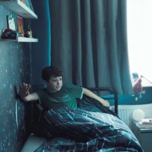 A cop aims a gun at a kid in his bed in Adolescence.