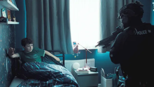 A cop aims a gun at a kid in his bed in Adolescence.