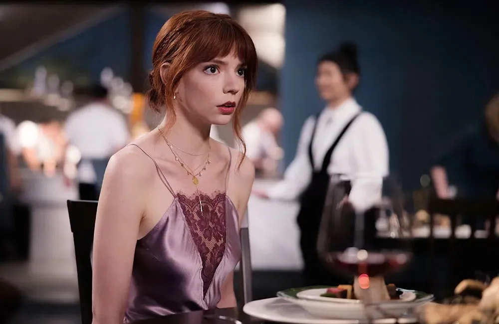 Anya Taylor-Joy sits at a table in The Menu.