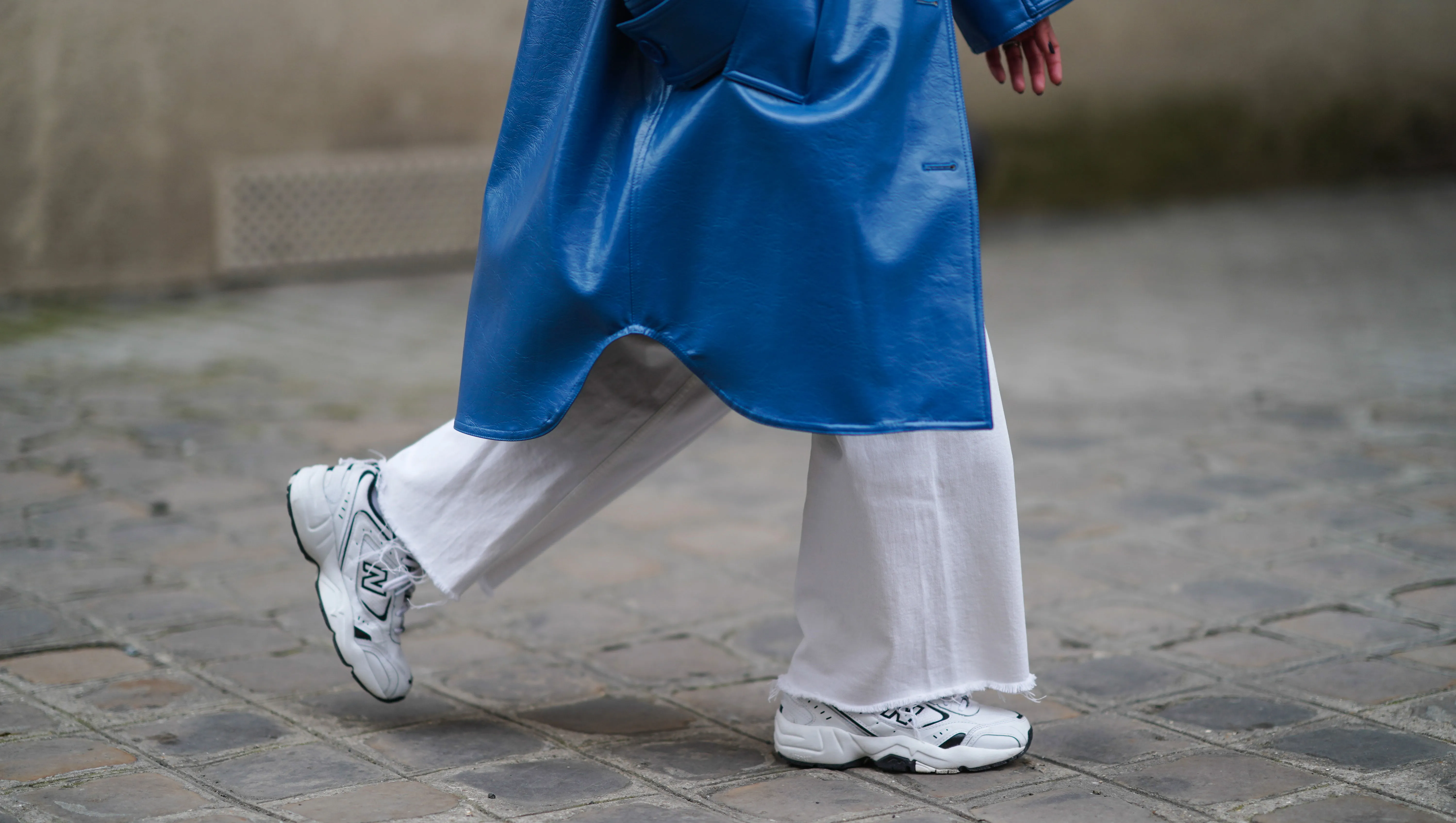 PARIS, FRANCE - MARCH 05: Alexandra Pereira wears a blue long trench coat from Stand Studio, white flare denim jeans from Zara, white sneakers shoes from New Balance, on March 05, 2021 in Paris, France. (Photo by Edward Berthelot/Getty Images)
