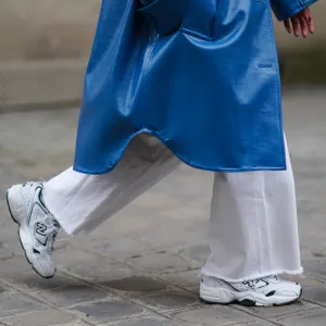 PARIS, FRANCE - MARCH 05: Alexandra Pereira wears a blue long trench coat from Stand Studio, white flare denim jeans from Zara, white sneakers shoes from New Balance, on March 05, 2021 in Paris, France. (Photo by Edward Berthelot/Getty Images)