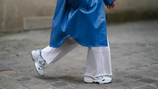 PARIS, FRANCE - MARCH 05: Alexandra Pereira wears a blue long trench coat from Stand Studio, white flare denim jeans from Zara, white sneakers shoes from New Balance, on March 05, 2021 in Paris, France. (Photo by Edward Berthelot/Getty Images)