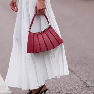 PARIS, FRANCE - MARCH 09: Amalie Bladt wears white pleated Lacoste midi skirt, a gold bracelet, a gold watch, shiny dark red Lacoste leather bag, outside Lacoste, during the Paris Fashion week Women's Fall/Winter 2025-2026 on March 9, 2025 in Paris, France. (Photo by Edward Berthelot/Getty Images)