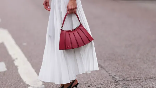 PARIS, FRANCE - MARCH 09: Amalie Bladt wears white pleated Lacoste midi skirt, a gold bracelet, a gold watch, shiny dark red Lacoste leather bag, outside Lacoste, during the Paris Fashion week Women's Fall/Winter 2025-2026 on March 9, 2025 in Paris, France. (Photo by Edward Berthelot/Getty Images)