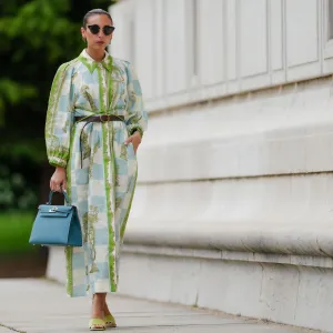 PARIS, FRANCE - MAY 12: Gabriella Berdugo wears sunglasses, earrings, a white blue and green checked long dress with long sleeves and floral print, a brown leather belt, a blue Kelly Hermes bag, pale pastel yellow mules / shoes with heart-shaped heels from Kat Maconie, during a street style fashion photo session, on May 12, 2024 in Paris, France.