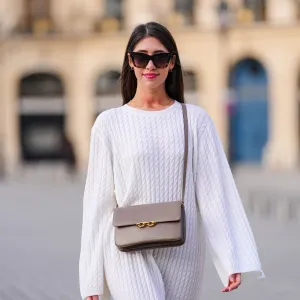 woman wearing loose white top and beige purse