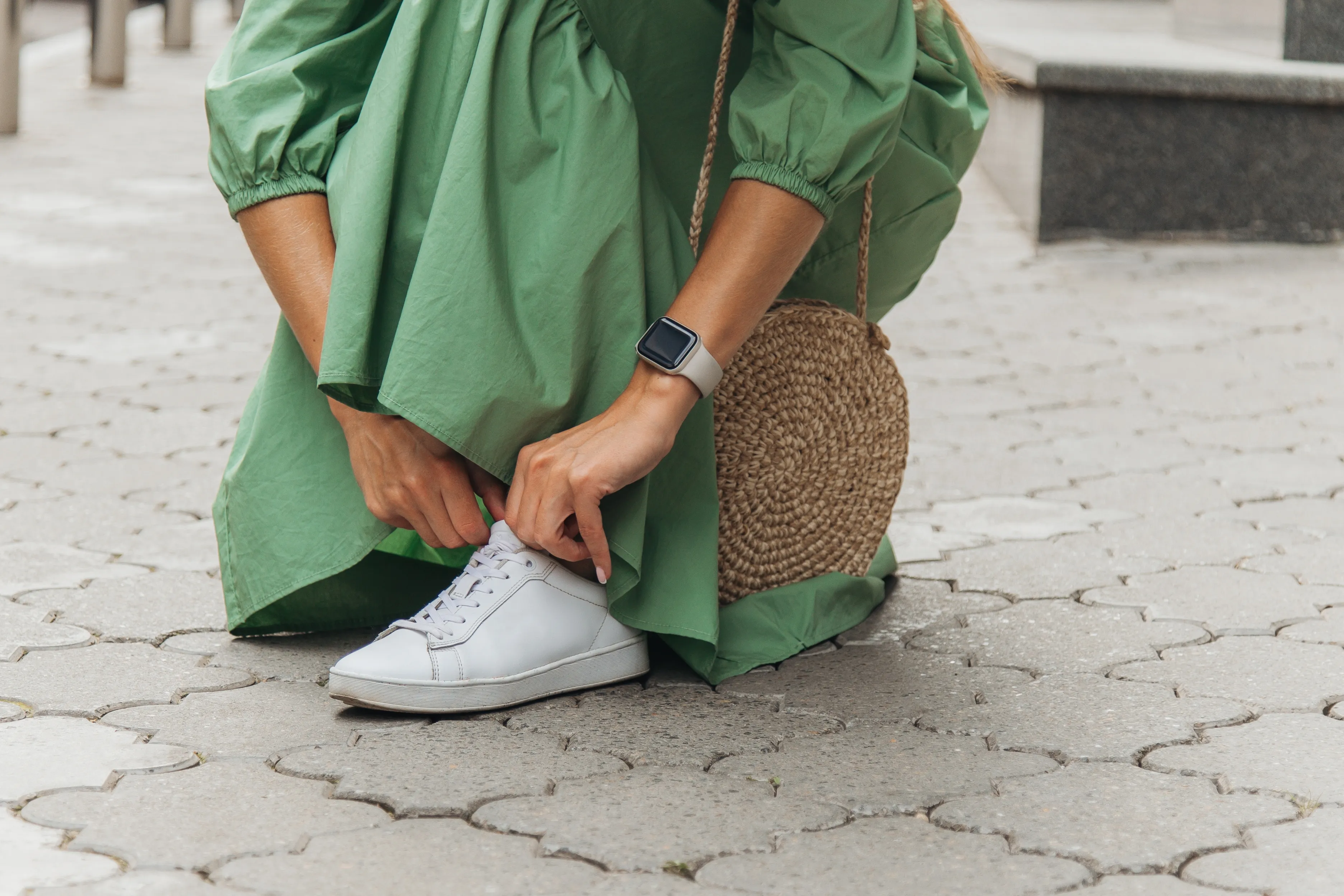 Young woman in a dress lacing her shoe.