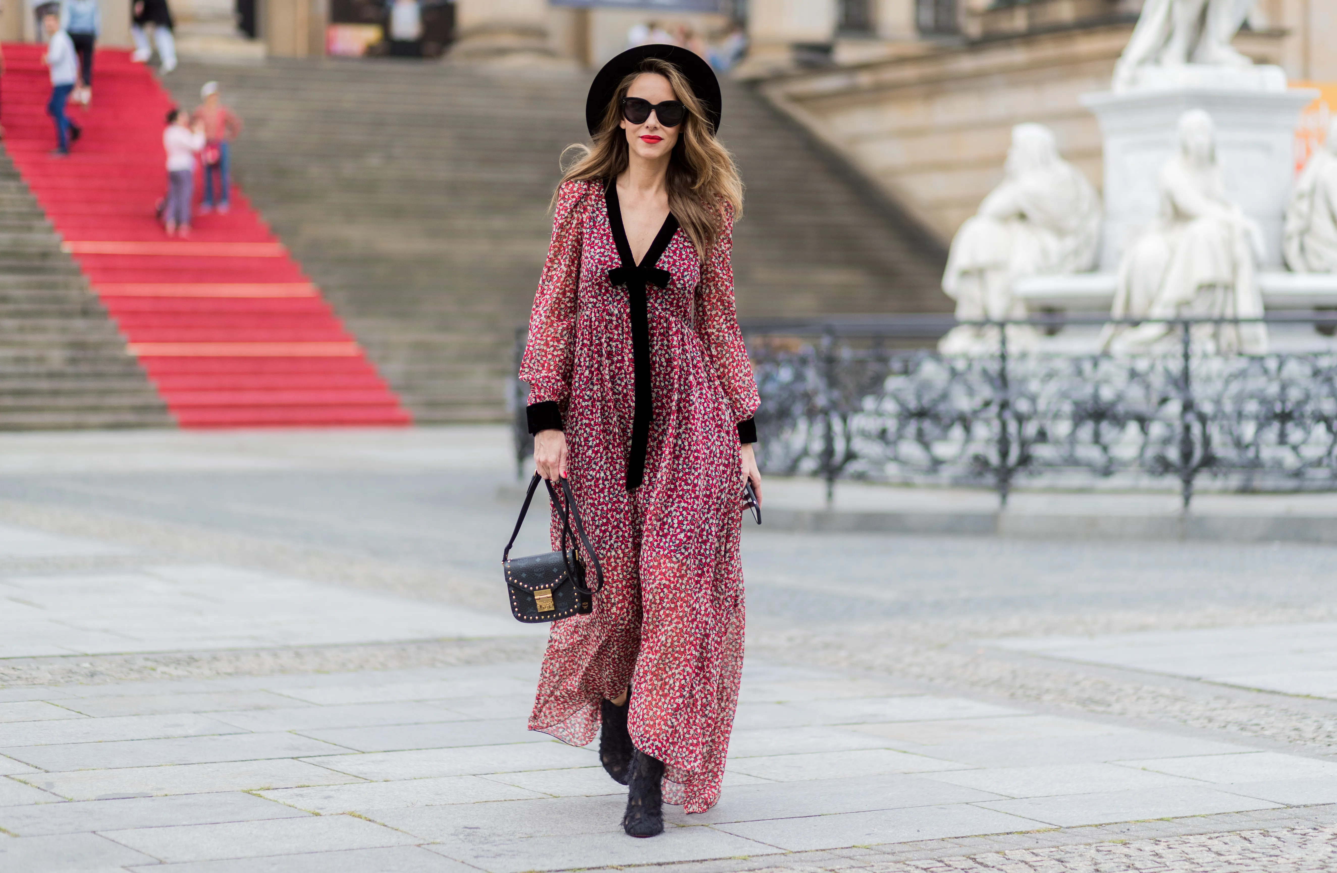 woman in red and black flowy dress and black hat