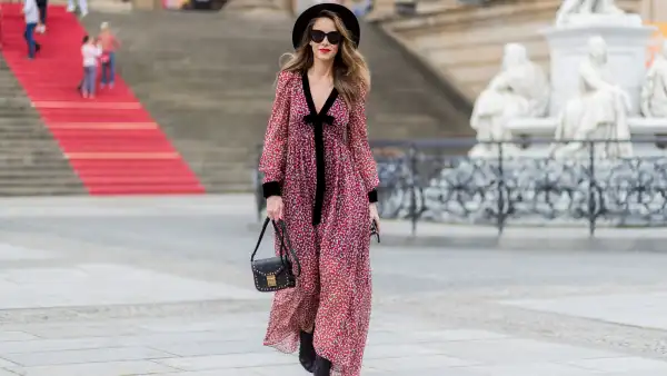 woman in red and black flowy dress and black hat