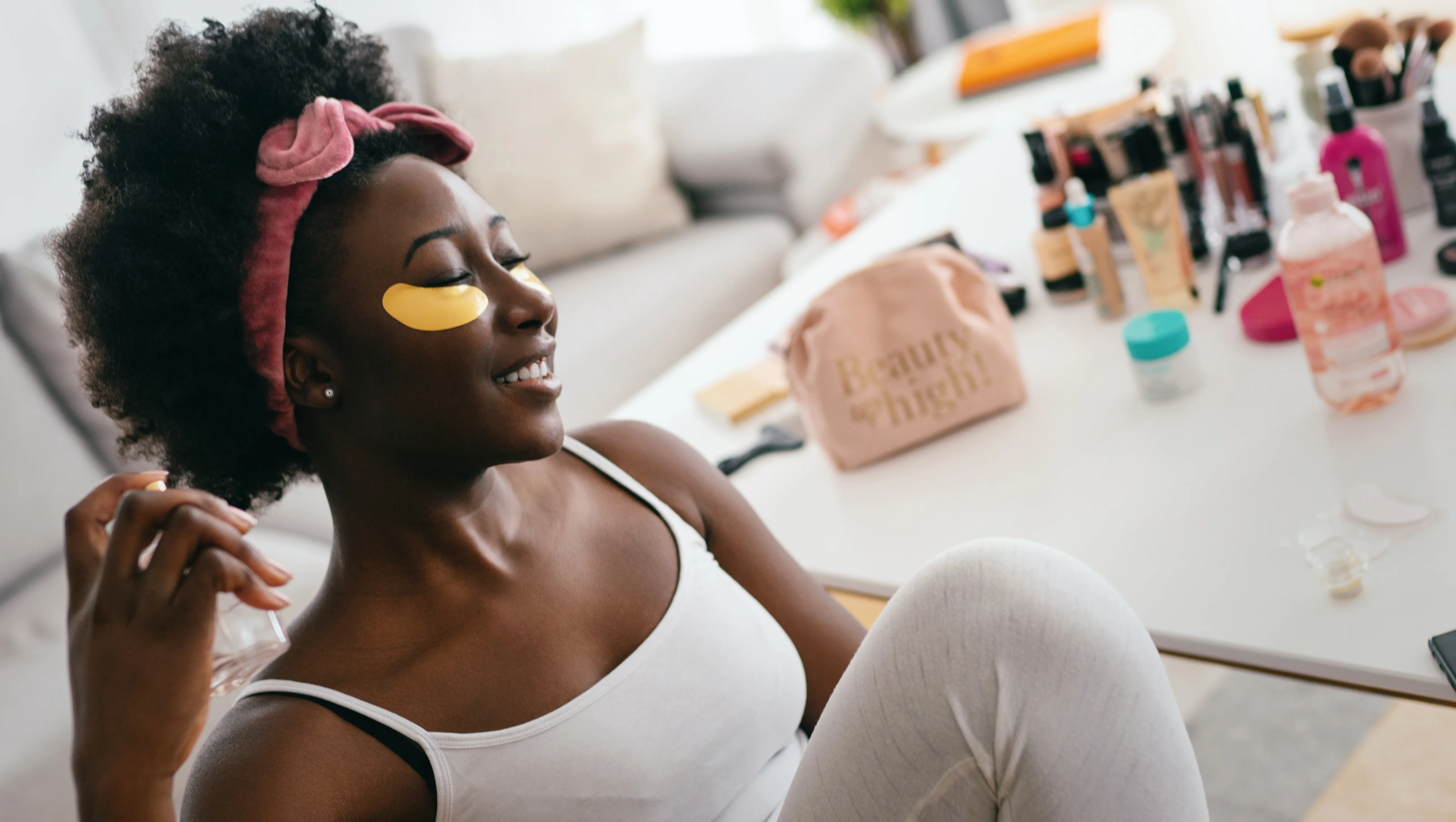 Beautiful young woman with under eye patches, sitting and enjoying the scent of a beautiful perfume.