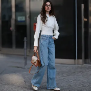 BERLIN, GERMANY - MARCH 21: Celine Bethmann seen wearing Miu Miu brown oval framed statement glasses, Cie Cie fitted ivory long-sleeve cotton henley top with a structured waist detail, Cie Cie high-waisted, light-wash wide-leg jeans that add a relaxed yet sophisticated touch, Cochinelle two-tone leather handbag in beige and brown, adding an elegant contrast and Alohas classic soft cream suede and light brown leather sneakers with a vintage-inspired silhouette, on March 21, 2025 in Berlin, Germany. (Photo by Jeremy Moeller/Getty Images)