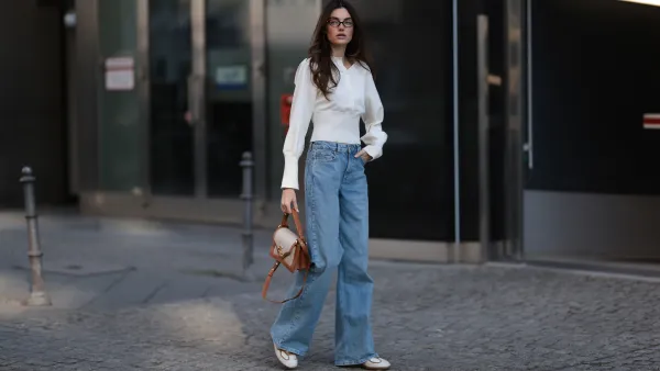 BERLIN, GERMANY - MARCH 21: Celine Bethmann seen wearing Miu Miu brown oval framed statement glasses, Cie Cie fitted ivory long-sleeve cotton henley top with a structured waist detail, Cie Cie high-waisted, light-wash wide-leg jeans that add a relaxed yet sophisticated touch, Cochinelle two-tone leather handbag in beige and brown, adding an elegant contrast and Alohas classic soft cream suede and light brown leather sneakers with a vintage-inspired silhouette, on March 21, 2025 in Berlin, Germany. (Photo by Jeremy Moeller/Getty Images)