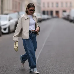 BERLIN, GERMANY - APRIL 12: Sophia Geiss seen wearing Saint Lauren black sunglasses, Uniqlo white cotton basic top, Calvin Klein blue denim baggy wide leg jeans pants, black leather belt, Meotine creamy white canvas jacket, Bottega Veneta creamy white / vanilla leather mini Jodie bag and Vagabond white leather mesh ballerinas, on April 12, 2024 in Berlin, Germany.