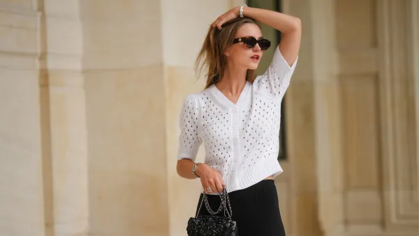 PARIS, FRANCE - MAY 12: Segolene Hyppolite wears sunglasses, a white wool cardigan / top from Agnes B, a white flower shaped bracelet, a Chanel bag with floral texture / details, black pants from Agnes B, during a street style fashion photo session, on May 12, 2024 in Paris, France. (Photo by Edward Berthelot/Getty Images)