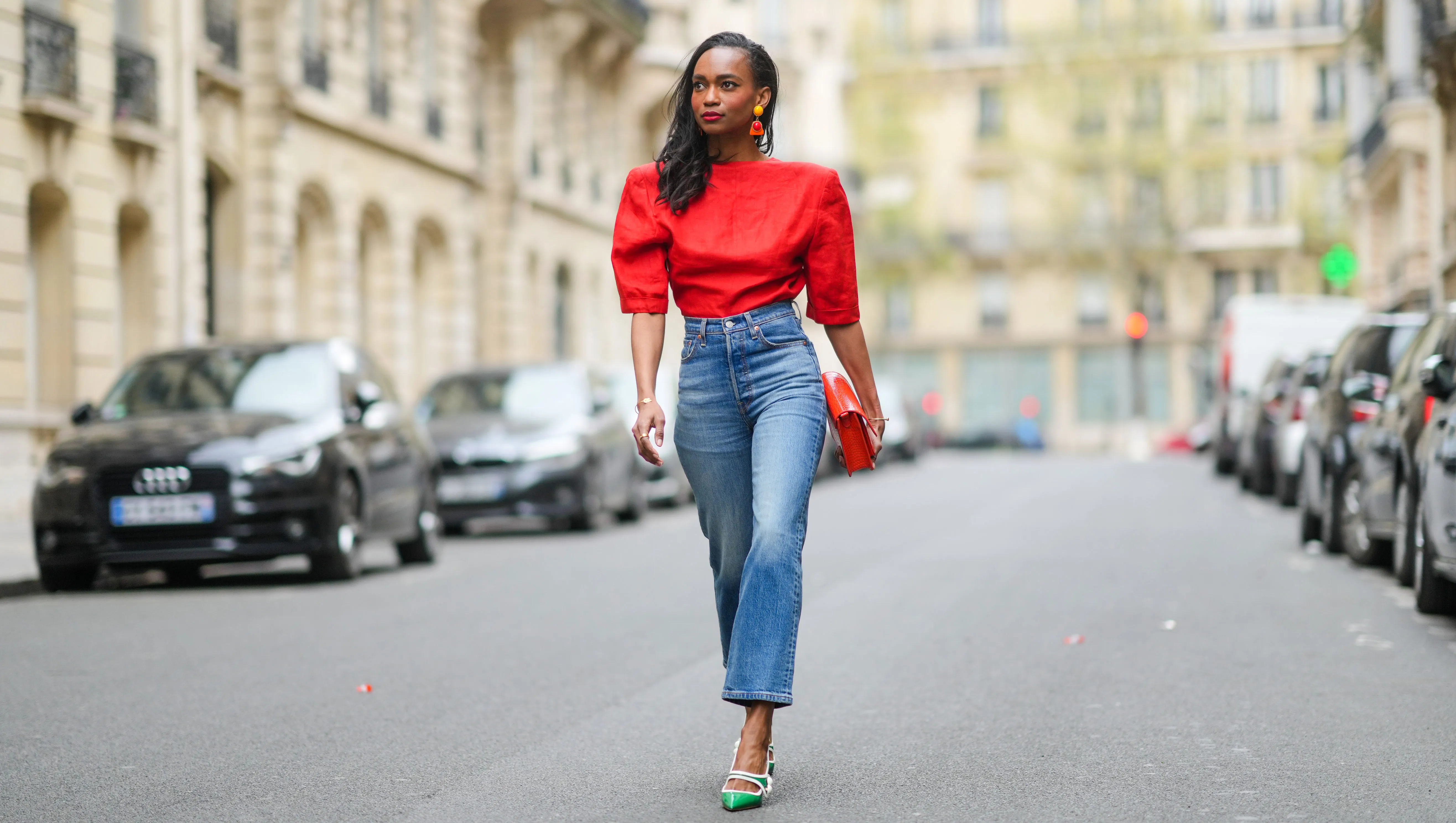 PARIS, FRANCE - APRIL 18: Emilie Joseph @in_fashionwetrust wears a red vintage linen power shoulder top worn backwards with plunging neckline in the back, blue denim high rise straight ribcage jeans from Levi's, green two-toned patent leather pointy sling back sandals / pumps from Miumiu, a red vegan embossed leather bag from Hvisk, clip-on Vintage colorblock ceramic earrings, on April 18, 2021 in Paris, France. (Photo by Edward Berthelot/Getty Images)