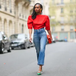 PARIS, FRANCE - APRIL 18: Emilie Joseph @in_fashionwetrust wears a red vintage linen power shoulder top worn backwards with plunging neckline in the back, blue denim high rise straight ribcage jeans from Levi's, green two-toned patent leather pointy sling back sandals / pumps from Miumiu, a red vegan embossed leather bag from Hvisk, clip-on Vintage colorblock ceramic earrings, on April 18, 2021 in Paris, France. (Photo by Edward Berthelot/Getty Images)