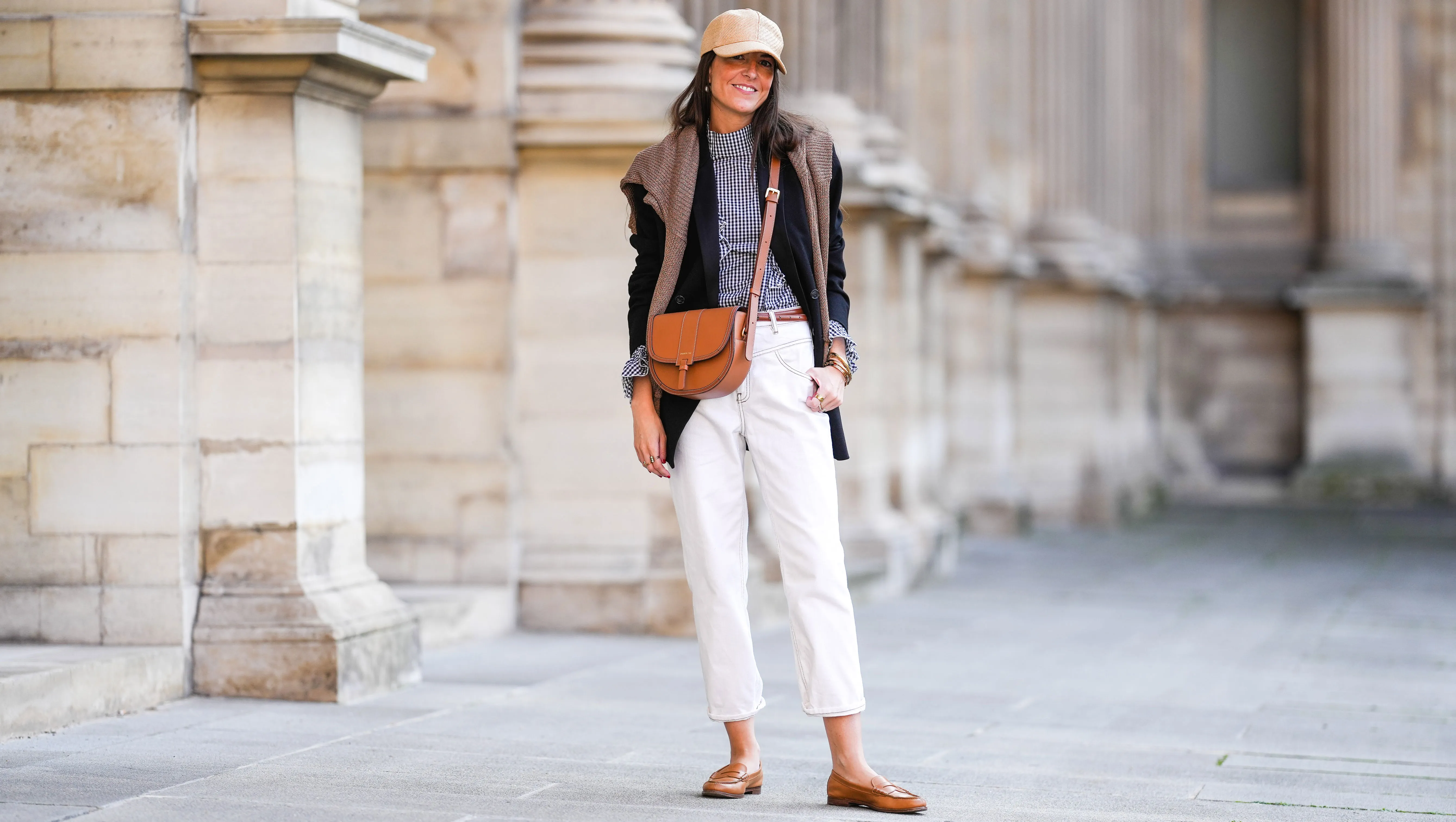 PARIS, FRANCE - OCTOBER 10: Alba Garavito Torre wears a wicker cap, a gingham black and white shirt with Long Sleeve Ruffles from Serendipia, Mom jeans in white by Maison 123 Paris, an oversized black blazer jacket by Munthe, caramel loafers shoes by Church’s, a caramel leather crossbody bag Windsor Paris64, a beige wool sweater over the shoulders, on October 10, 2021 in Paris, France. (Photo by Edward Berthelot/Getty Images)