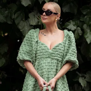 COPENHAGEN, DENMARK - AUGUST 9: Justyna Czerniak wears black sunglasses, a green embossed pattern puffy short sleeves long dress, beige and green khaki Loewe, brown shiny leather shoes outside Stine Goya during the Copenhagen Fashion Week Spring/Summer 2024 on August 9, 2023 in Copenhagen, Denmark. (Photo by Raimonda Kulikauskiene/Getty Images)