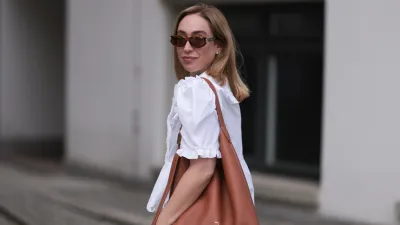 BERLIN, GERMANY - JUNE 11: Sonia Lyson is seen wearing sunglasses with havana frame from Givenchy, silver earrings, a golden necklace, a white blouse with puffed sleeves and ruffled details from Horror Vacui, cream-white wide linen pants from Zara and the “Low Key Hobo” bag in brown leather from Louis Vuitton on June 11, 2024 in Berlin, Germany. (Photo by Jeremy Moeller/Getty Images)