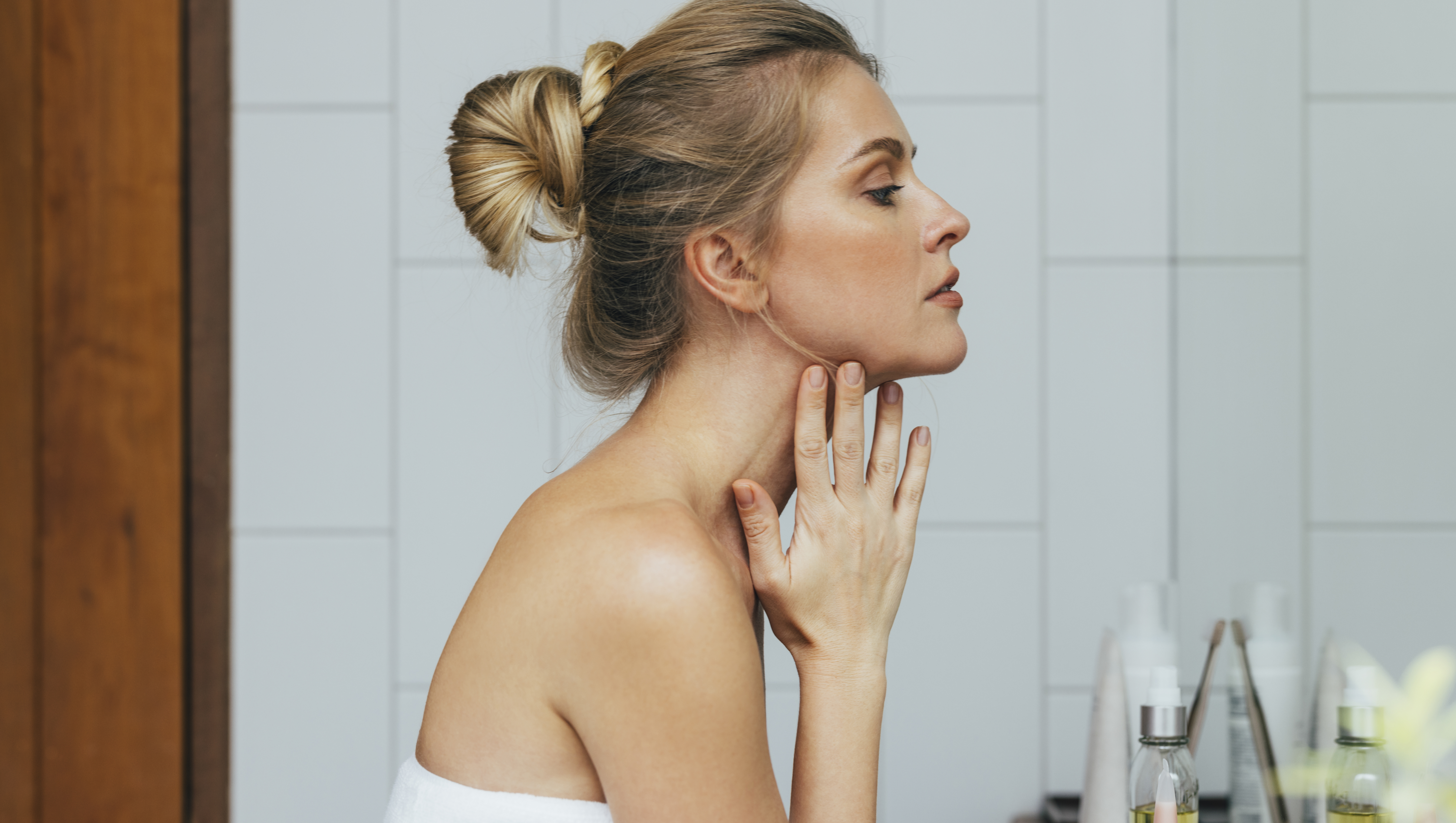 Young Caucasian woman looking herself in the mirror, after a shower.