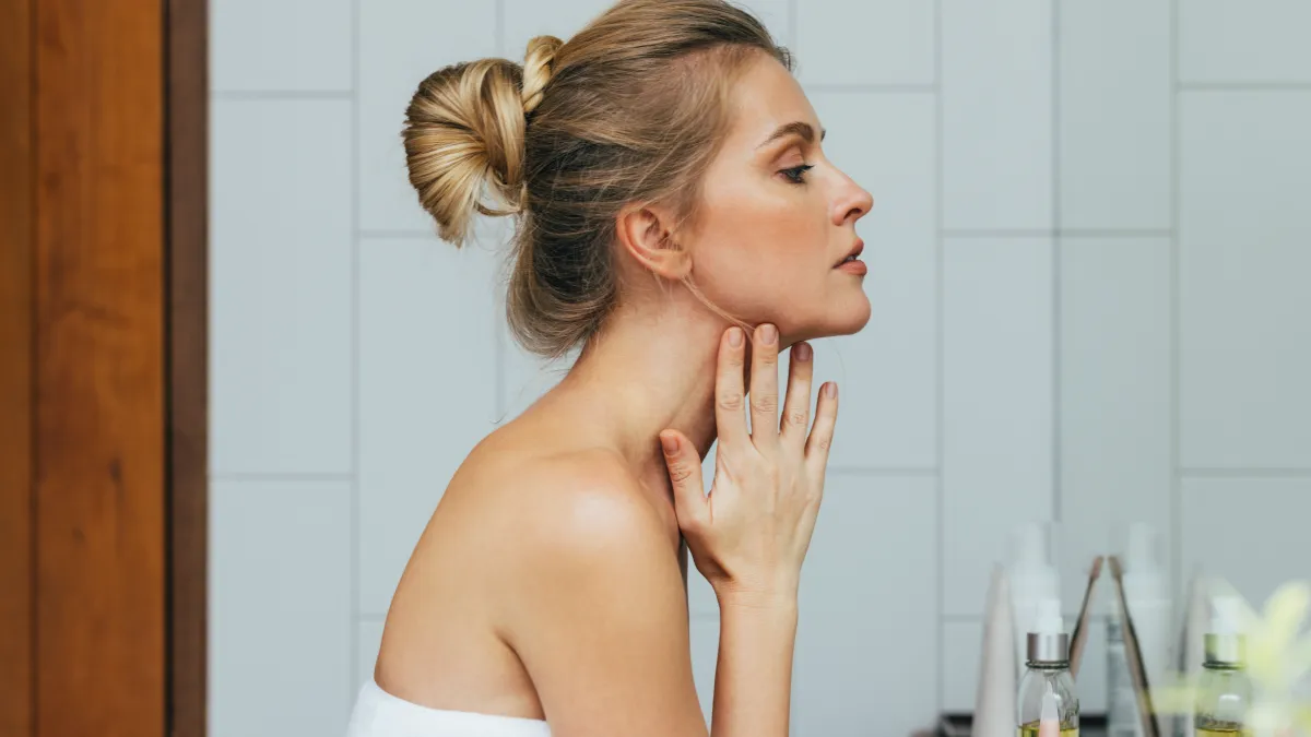 Young Caucasian woman looking herself in the mirror, after a shower.