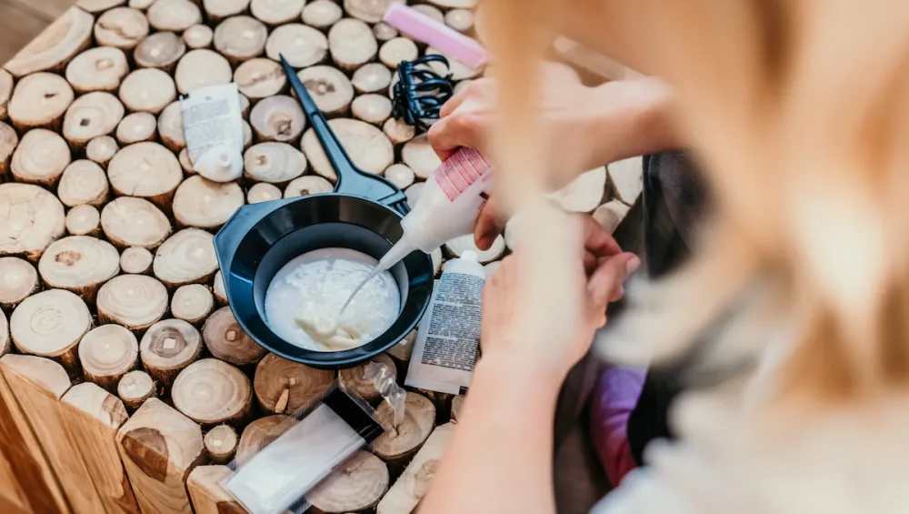 Hand of woman pouring hair dye mixing ingredient in bowl