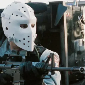 A man wearing a mask aims his gun in Heat.