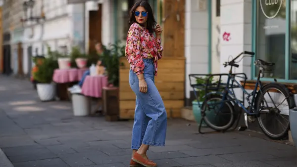 Anna Wolfers wearing colorful floral blouse, sunglasses, blue jeans and orange espadrilles on May 01, 2021 in Hamburg, Germany.