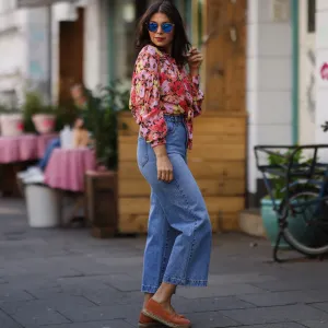 Anna Wolfers wearing colorful floral blouse, sunglasses, blue jeans and orange espadrilles on May 01, 2021 in Hamburg, Germany.