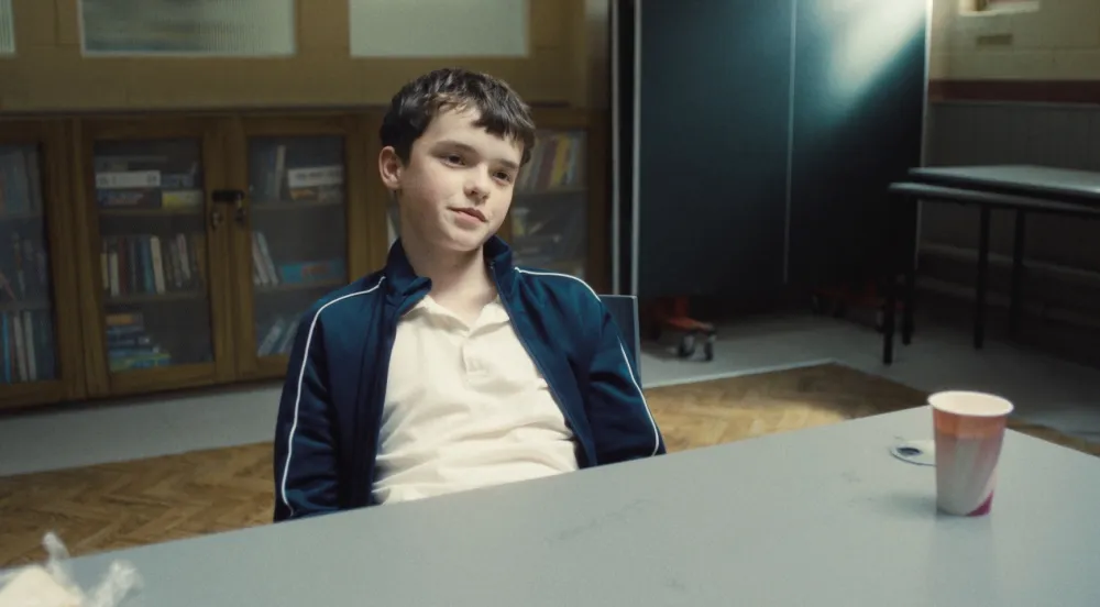 A boy sits at a table in Adolescence.