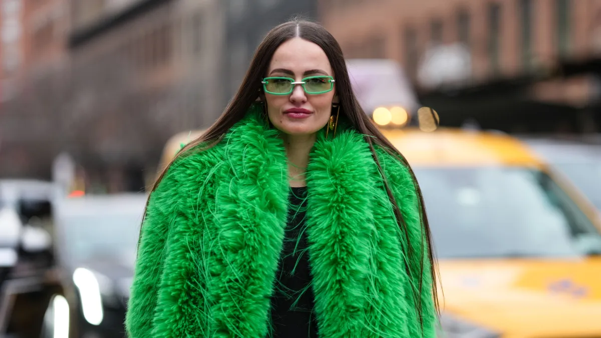 NEW YORK, NEW YORK - FEBRUARY 08: A guest wears bright green sunglasses, bright green faux fur coat, shiny black straight leather pants, outside Alice + Olivia, during the New York Fashion week Fall/Winter 2025 on February 8, 2025 in New York, New York. (Photo by Edward Berthelot/Getty Images)