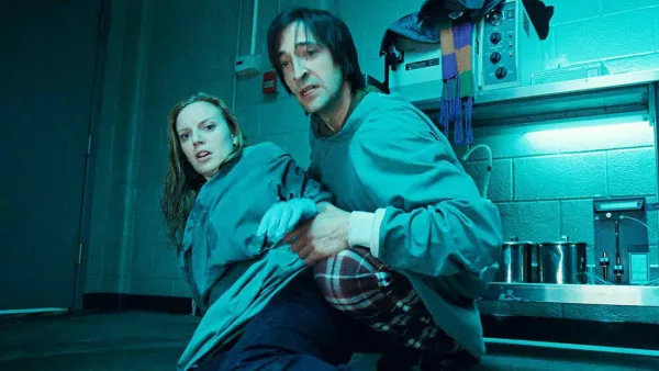 A man and a woman lean back in terror in Splice.