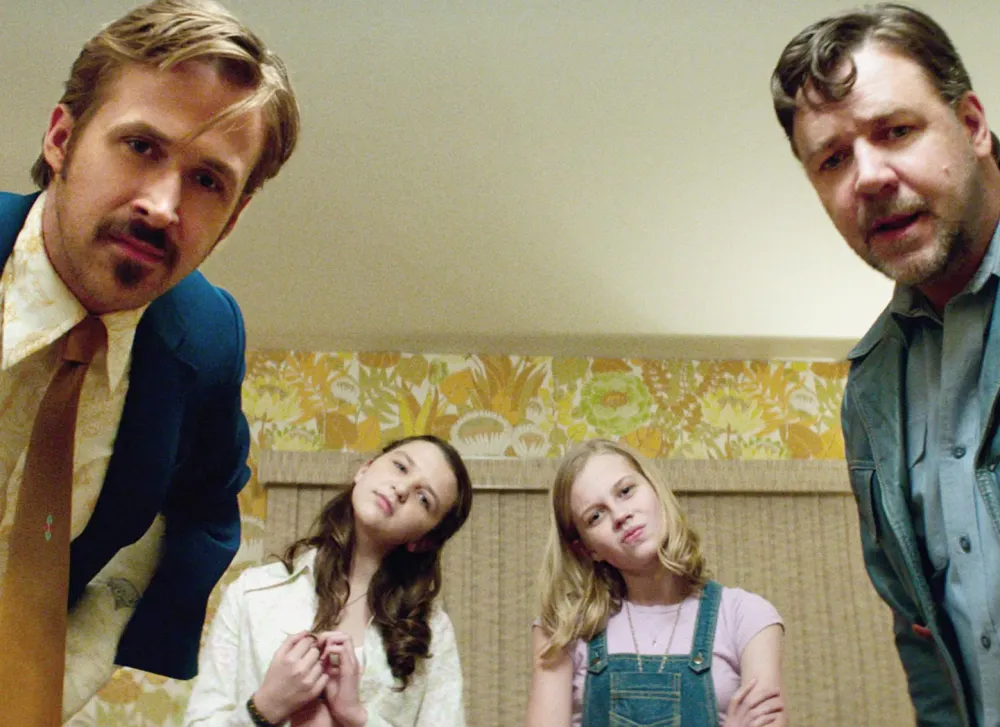 Two men and two girls lean in toward the camera in The Nice Guys.