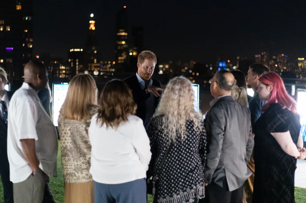 Prince Harry talks with a group of people at an NYC memorial installation