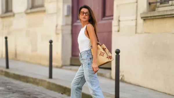 PARIS, FRANCE - JULY 20: Alexandra Pereira wears brown sunglasses from Tod's, a white ribbed tank top, a beige large wicker bag from Vuitton with printed monograms, pale blue denim ripped jeans pants, brown leather Hermes Oasis sandals / shoes, on July 20, 2021 in Paris, France. (Photo by Edward Berthelot/Getty Images)