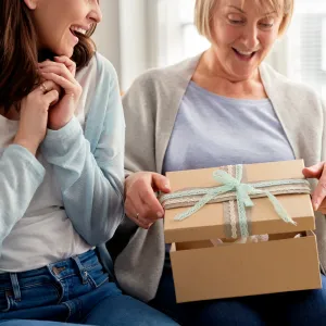 Excited adult daughter waiting for mom to open the gift